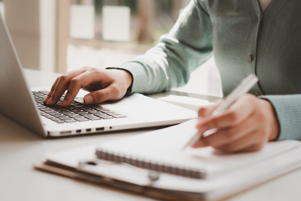 Person arbeitet am Laptop und notiert Details zu den AGB eines Arval Auto Abos.